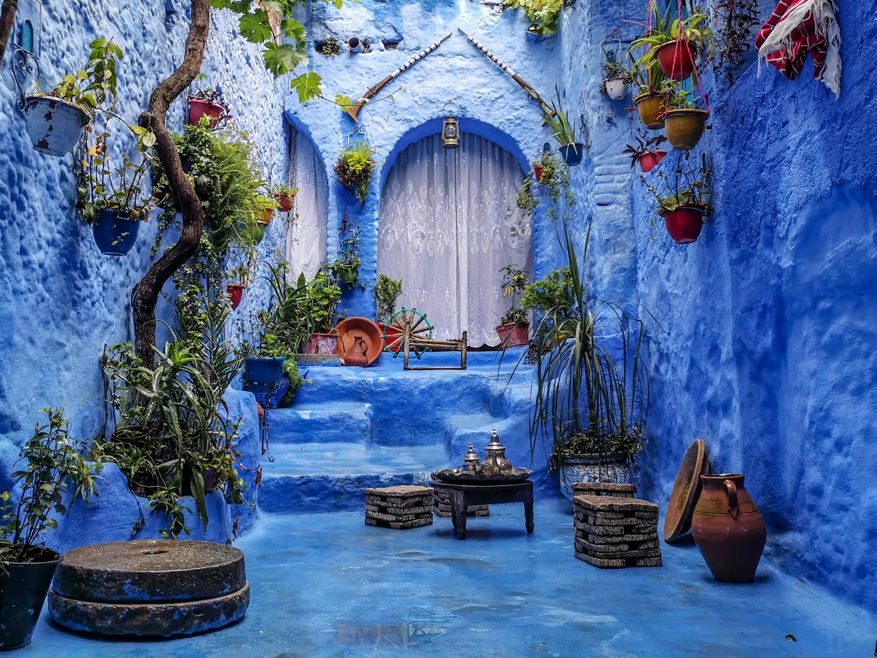 A blue courtyard with potted plants and traditional decor in Chefchaouen, Morocco